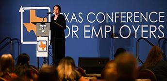 Woman stands at the podium giving a speech at the Texas Conference for Employers