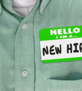 Green button down shirt with a sticker reading, "Hello, I am a New Hire"
