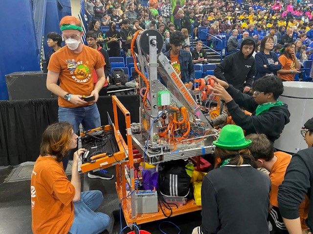 youth robotics team in orange uniform
