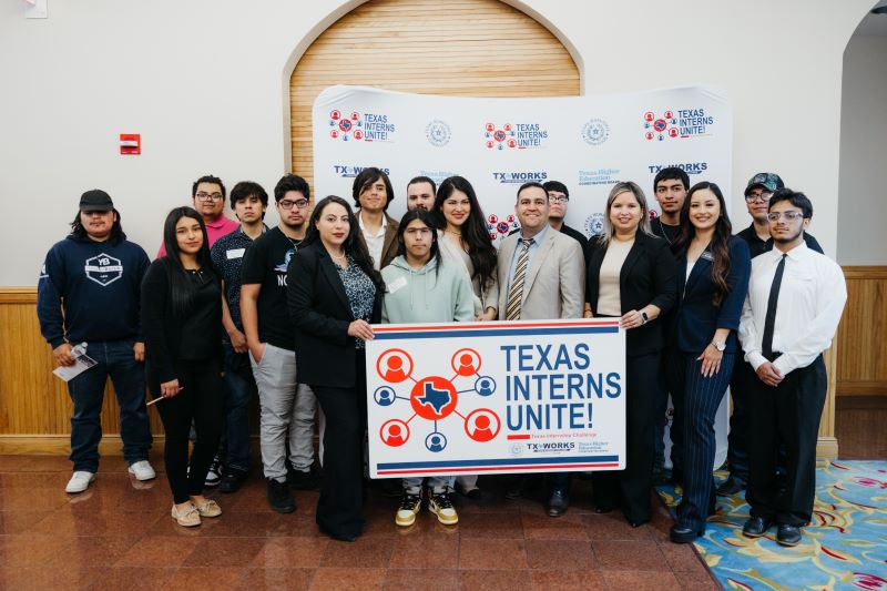 Texas Interns Unite participants pose for a photo while holding a Texas Interns Unite banner