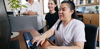 Woman with disability using special keyboard and computer.