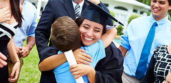 Woman in cap and gown hugging a family member.