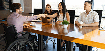 Man in wheelchair greets panel of employers.